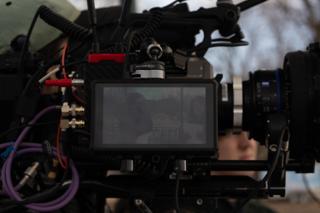 The camera monitor mid-take, the framed shot on screen and a 35mm prime mounted alongside