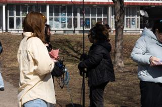 The actor in the yellow shirt talking with the sound recordist, boom stand and cable coiled between them