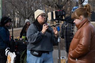 Camera assistant setting the follow focus on the rig, the camera cart and the company behind
