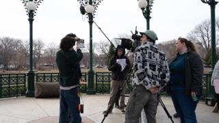 A grey card held up in front of the lens while the operator and the script supervisor watch
