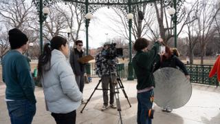 The company gathered behind the camera, the round reflector carried in to the mark