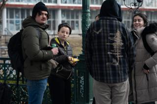 Five of the company gathered around the green lamp post with drinks and snacks between takes