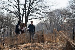 Three of the company walking the fence line with scripts in hand, dry grass and bare branches behind them