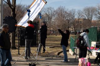 The white bounce raised on stands beside the chalkboard while a crew member points out the angle