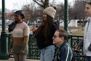 Three of the background cast waiting on their marks in the bandstand, one throwing a peace sign