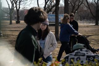 Two of the crew carrying gear across the grass behind the dressed table, the company waiting in the foreground