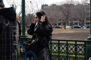 Sound recordist settling her headphones on, the mixer bag and coiled cable slung at her hip