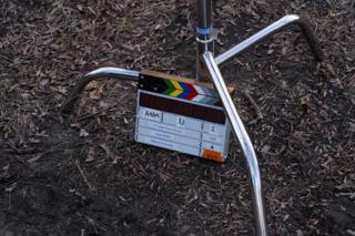 The slate propped against the tripod legs on the leaf litter, marked up for scene 8A
