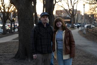 Two of the company standing together on the path as the sun drops behind the trees