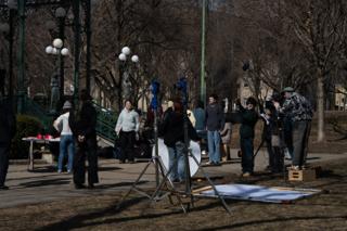 Wide of the setup by the bandstand — stands, bounce boards laid out on the grass and the camera up on an apple box