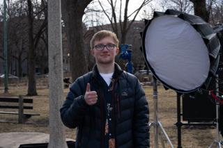A crew member giving a thumbs-up beside the big round softbox on its stand