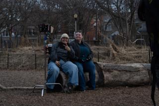 Two of the crew perched on the log beside the camera, grinning at the lens