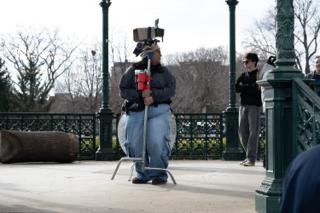 Operator balancing the camera on a monopod in the middle of the bandstand, waiting for the take