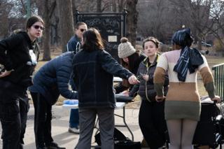 The company crowded round the folding table, a chalkboard sign propped on the railing behind