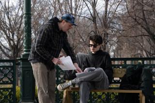 Director leaning over the bench to work through a page with the actor