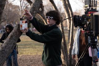 The clapperboard held up to the lens again, the light gone gold between the trees