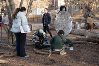 The wider setup: script supervisor watching from the left, operator down on the ground, reflector held steady behind