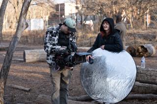 Operator checking his frame while a crew member grins over the silver reflector she is holding