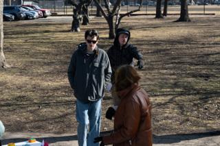 An actor listening as notes are given out on the path, the company gathered round