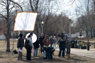 The diffusion frame raised high on stands over the crew, the camera operator lining up the shot from an apple box