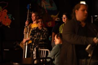 Crew gathered around a light stand in front of a brightly painted mural