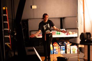 Crew member laying out drinks on a craft services table beside stacked supplies