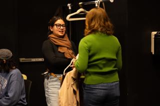 Wardrobe crew member going over a costume change at the clothing rail