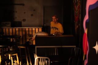 The bar-room set between setups, an actor waiting behind the counter beneath a painted mural