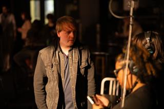 Actor waiting beside the camera team while the operator lines up the next shot
