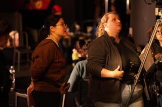 Two crew members watching the action from behind the camera as a take runs