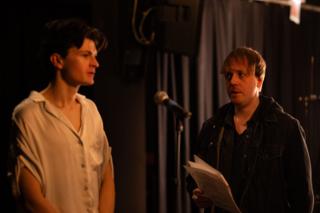 Director giving notes to the lead actor beside the microphone stand