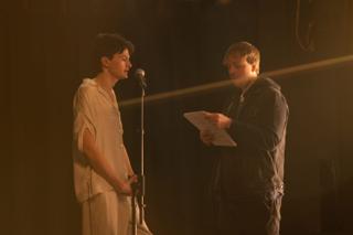 Director going over script pages with the lead actor at the microphone