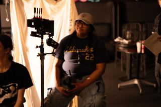 Camera assistant at the follow focus in front of the lit bounce