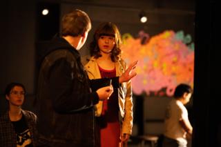 Director talking a scene through with an actor in front of the brightly painted mural