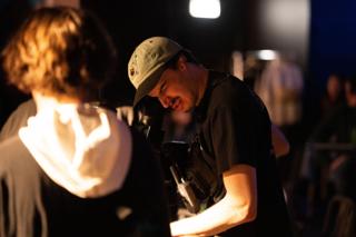 Camera operator working in close on an actor lit by a warm practical lamp
