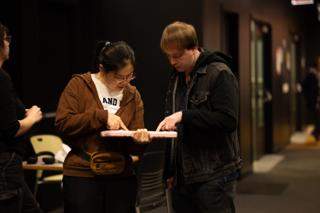 Two crew members inspecting a pink prop together in the corridor outside the stage