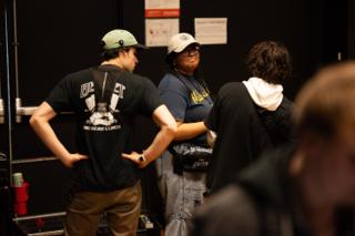 Three crew members standing in a huddle backstage between setups