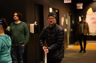 Cast and crew waiting in the corridor between takes, one leaning on a handrail