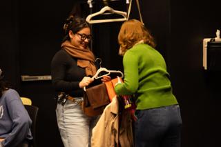 Wardrobe crew sorting coats and bags on hangers backstage