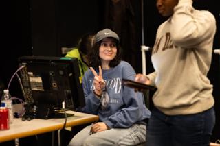 Crew member at the monitor bench raising a peace sign to the camera between setups