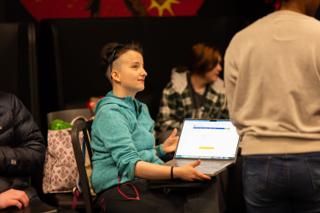 Crew member turning from a laptop to talk with someone off camera in the production area