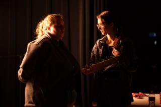 The same pair a moment later, the crew member turning the clipboard toward the performer