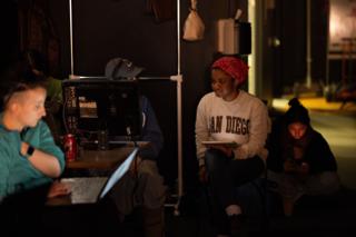 Video village between takes, crew watching the monitor while another works at a laptop nearby