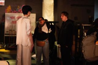 Three crew members talking together in the holding area, gear and cases stacked around them