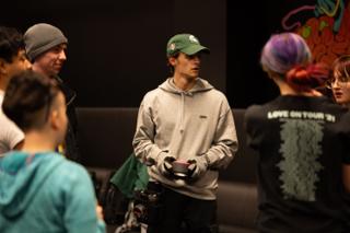 Crew member standing among the group with gloves and gear in hand, listening during a reset