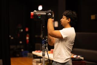 Gaffer adjusting a light on its stand, gloved hands steadying the fixture