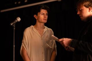 Actor at a microphone listening as the director reads from a script page