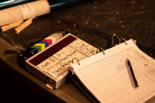 Clapperboard marked for If I Could Touch the Sun resting beside a shot log and pen on a table