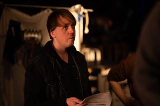 Crew member holding a script page and looking off toward the set