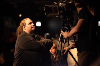 Crew member looking up at a cinema camera as the operator sets up the shot